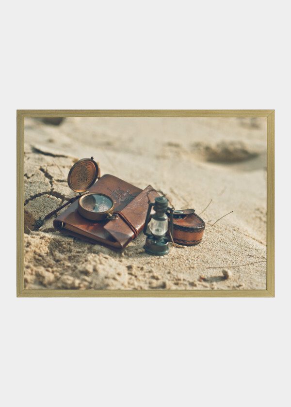 COMPASS AND LOGBOOK IN THE SAND