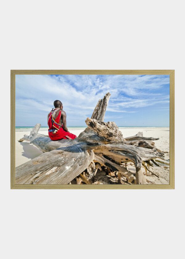MAN OF THE MAASAI TRIBE SITS ON THE SHORE OF THE INDIAN OCEAN