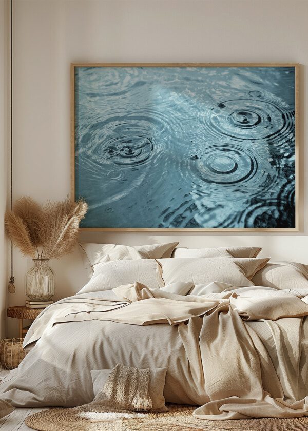 RAIN DROPS RIPPLING IN A PUDDLE WITH BLUE SKY REFLECTION