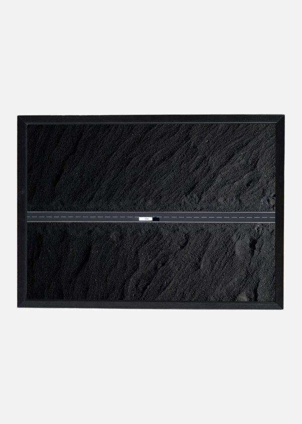 THE ROAD WITH WHITE LINES IS SURROUNDED BY BLACK VOLCANIC LAVA