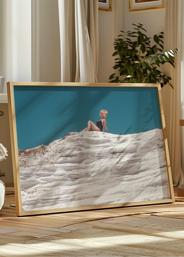 A BEAUTIFUL BLONDE GIRL SITS ON THE EDGE OF A CLIFF OF A QUARTZ QUARRY AGAINST A BLUE SKY
